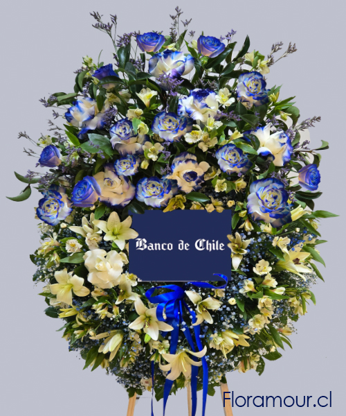 Magnífica ofrenda deluxe con rosas azules tratadas y flores de complemento. Incluye atril y logo de empresa, imagen libre o retrato. Corona Exclusiva Floramour